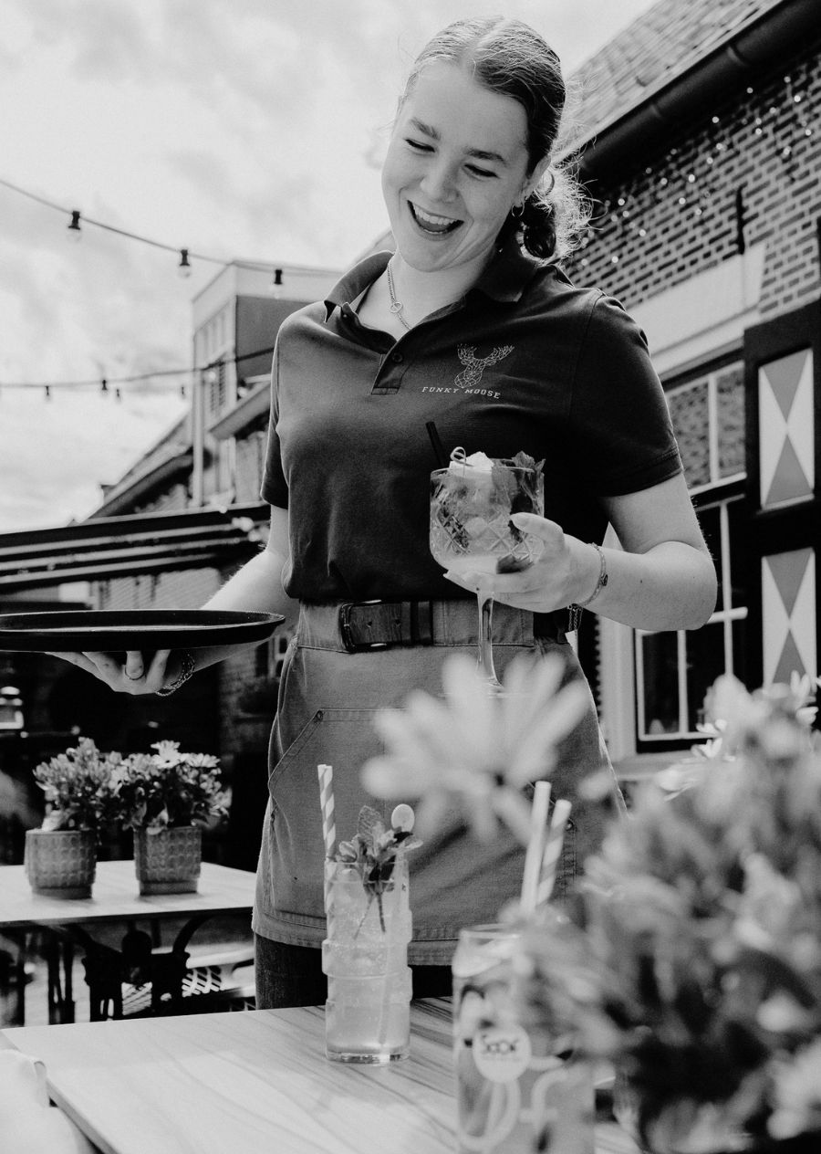 Bediening serveert drinken uit op het terras