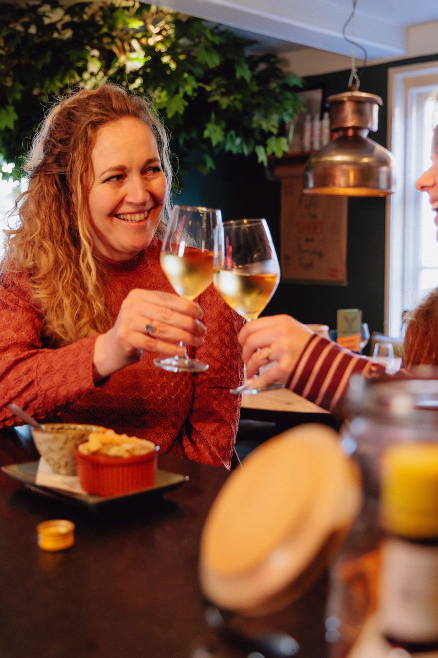 Een lachende vrouw aan de bar die proost met een alcoholvrije wijn