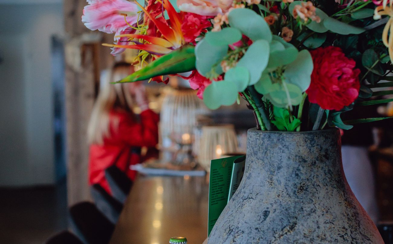 Een vaas met kleurige bloemen op de bar